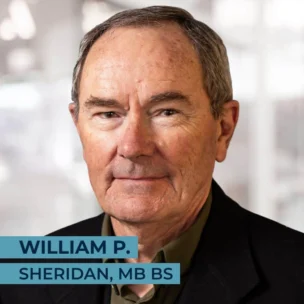 Portrait of a man with grey hair, wearing a dark jacket and a collared shirt. Text overlay: "William P. Sheridan, MB BS" on the bottom left of the image.