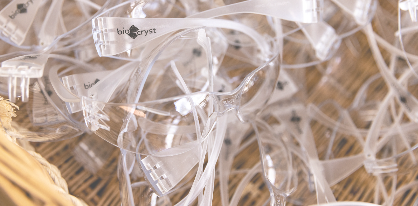 A pile of transparent safety goggles with the logo "BioCryst" on the frames.