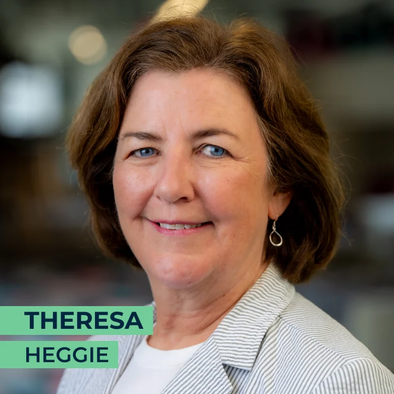 A woman with short brown hair wearing a light striped blazer and earrings is smiling; the name "Theresa Heggie" appears in text at the bottom left.