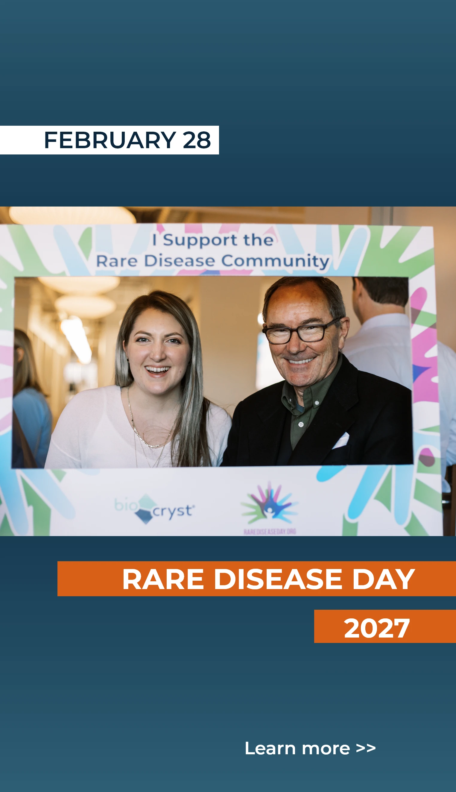 A smiling man and woman pose behind a “I Support the Rare Disease Community” frame for Rare Disease Day, February 28, 2027.